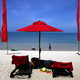 A photo of two lounge chairs on a beach.
